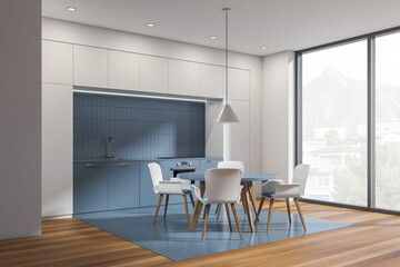 White and blue kitchen interior with table and chairs, wooden floor