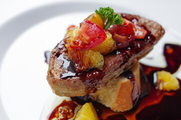 Seared foie gras on baguette bread with black sauce and grapefruit