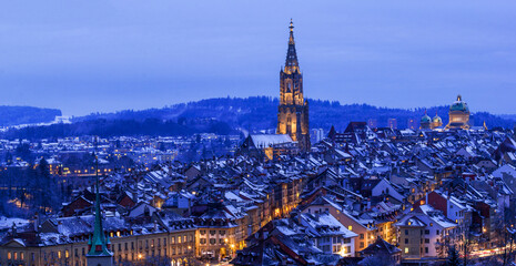 Panorama of the town center of Bern in winter blue hour with snowy and illuminated buildings,...