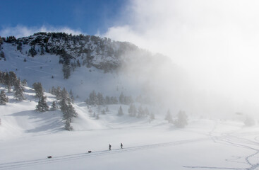 paysage alpin: Chamrousse et le massif de Belledonne sous la neige en hiver avec des nuages dans la vallée