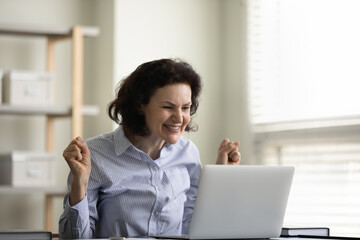 Happy excited middle aged female business leader celebrating achieve, success, high result, winning...