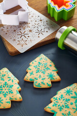 Christmas tree shaped cookies with snowflakes pattern, stencil, cookie cutters, rolling pin,...