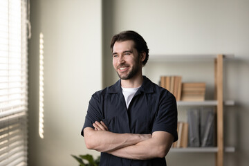 Happy thoughtful entrepreneur, business man in casual standing with folded arms, looking at window in good thoughts, dreaming of successful career, project vision, company future. Head shot portrait