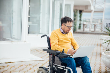 a man with disabilities in a wheelchair works on a laptop in the Internet
