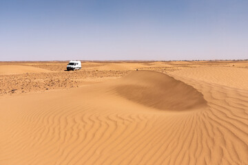 Fototapeta na wymiar In the Sahara Desert in Morocco. A 4x4 van in the middle of the dunes near erg Chegaga