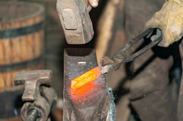 Detail shot of hammer forging hot iron at anvil