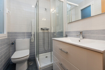 Bathroom with white cabinet, mirror and shower screen in vacation rental apartment