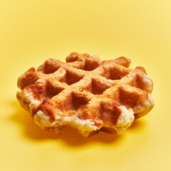  Single delicious waffle over yellow background