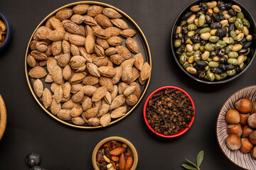 dried beas edamame, shelled almonds, dried fruits and oats on black background