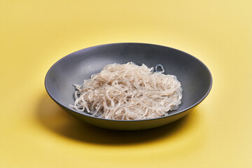  Plate of white rice noodles over yellow background