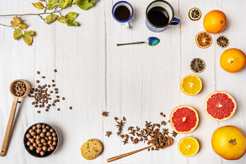 Top view of still life with variety of citrus fruits, chocolate bonbons, paper stars, coffee cups, chocolate cookies and wooden table with star anise and leaves