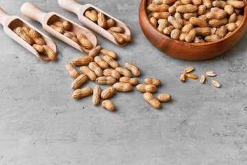 Image of wooden spoons with peanuts on a concrete surface
