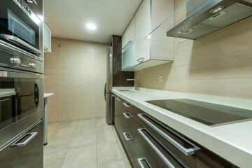Kitchen with Silestone countertop with ceramic hob with extractor hood and appliances and cream...