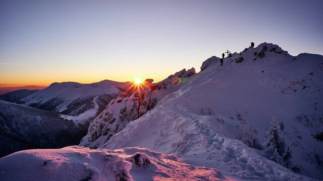 Sunset from the top of a snowy mountain. People move on top of the mountain. 