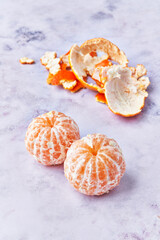  Two peeled tangerines at marble surface