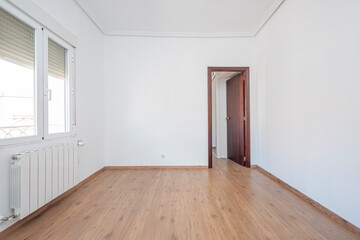 Empty room with chestnut parquet floors and white painted walls