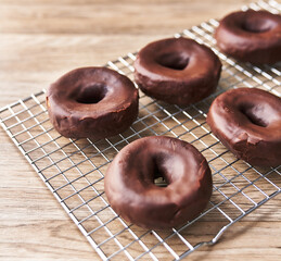  Oven tray with chocolate doughnuts on a wooden surface