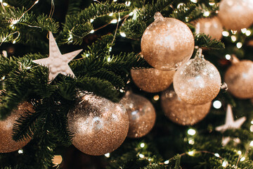 Christmas tree decorated with golden shiny Christmas balls and star. Magic cozy details, festive winter background
