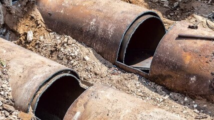 Construction works on large iron pipes at a depth of excavated trench