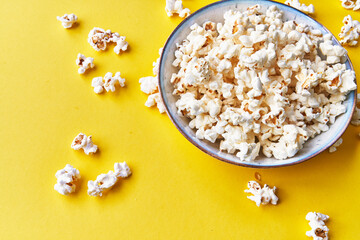  Bowl of salty popcorns on a yellow background