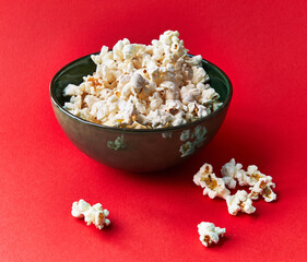  Bowl of salty popcorns on a red background