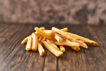  Bunch of french fried potatoes on a wooden surface