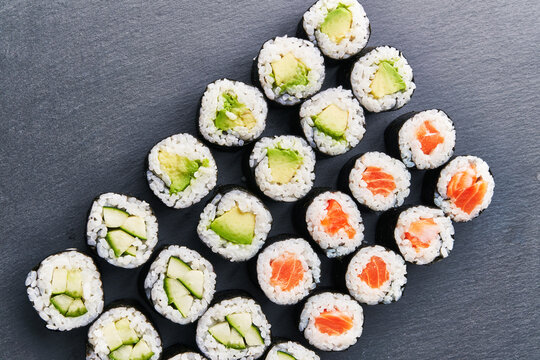  Group of avocado, salmon and cucumber sushi makis on a concrete surface