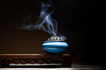 Smoke from burning incense sticks standing on lotus incense holder