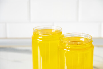 Two jars of clarified ghee butter on kitchen tile background