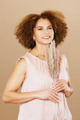 Fashion studio portrait of stylish middle age woman posing on beige background, 50 - 55 year old...
