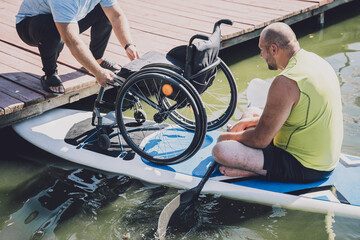 Person with a physical disability ride on sup board with his wheelchair