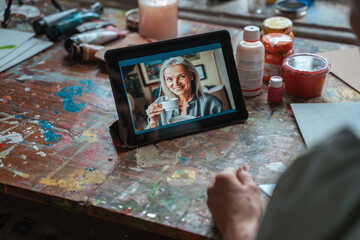 Woman chatting with her bestie using tablet while sitting at home after the drawing