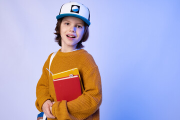 Back to school. Modern school boy with backpack and books on neon background