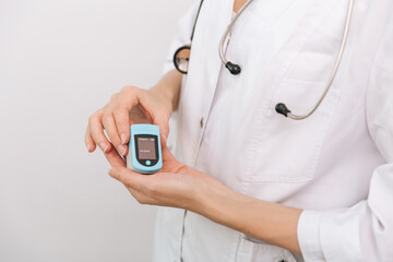 Pulse oximeter with hand of doctor isolated on white. Measuring oxygen saturation, pulse rate and oxygen levels. The concept of portable digital device to measure person's oxygen saturation.