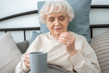 Senior female eating vitamins and drinking water during the morning