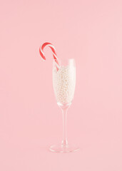 Creative Christmas arrangement made of a champagne glass with pearls on a pastel pink background. Minimal New Year concept. Candy party inspiration.