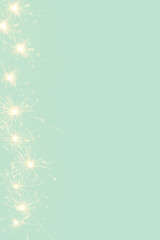 Creative background made of.sprinklers sparks on a mint green backgrund. Minimal New Year concept with copy space.