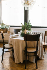 A dining table with wooden chairs, decorated and served for Christmas dinner against the background of a large window in the house
