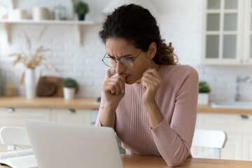Unhappy thoughtful woman wearing glasses looking at laptop screen close up, biting nail, working...