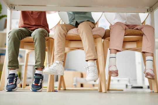 Group of school children sitting on chairs at desk during a lesson in the classroom