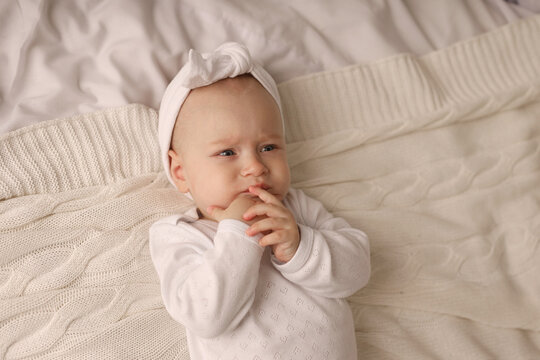 a 6-month-old baby lies in a crib in the nursery with white clothes on her back and laughs, looks at the camera, the morning of the child, the concept of children's goods. high-quality photography