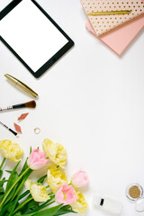 Springtime flat play with keyboard, notebooks, cosmetics, tablet make-up and bunch of pink and yellow tulips on a light background with copy space. Spring concept for a blog. Greeting Card