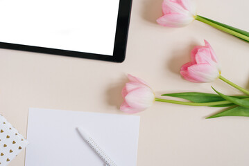 Obraz premium Spring background flat lay of pink tulips with tablet mockup, copy space for text. Mother's Day or Valentine's Day