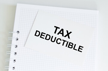 White card on the notebook on the table with text Tax Deductible