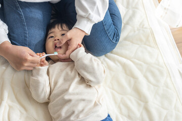 母親に歯を磨いてもらっている赤ちゃん（1歳4か月、女の子、日本人） - obrazy, fototapety, plakaty