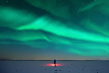 Türaufkleber Tourist with red flashlight on snowy field against the backdrop of incredible starry sky with Aurora borealis. Amazing night landscape. Northern lights in winter field © Ivan Kmit