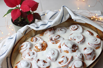 cinnamon rolls in sauce on a light background with Christmas flower and lights