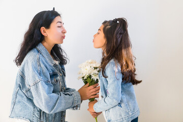 Happy young mother getting flowers from daughter little girl kid during mothers day. Tender moment of motherhood