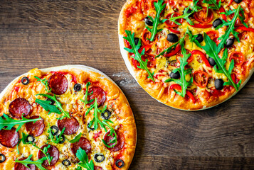 Pepperoni Pizza and Pizza with Mozzarella cheese, Tomatoes, pepper, olive, Spices and Fresh arugula. Pizza Margherita or Margarita on wooden table