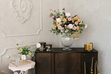 Classic bedroom interior. A brown wooden chest of drawers, flowers in a glass vase, and a white bedside table